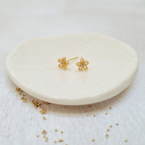 Gold daisy flower stud earrings in a bottle