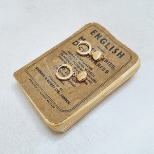 Gold Shell Huggie Earrings in a bottle