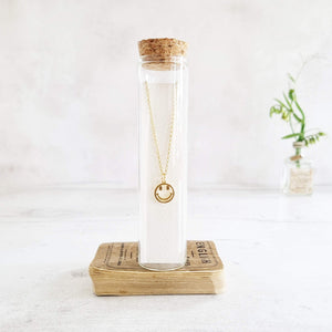 Gold smiley face necklace in a bottle
